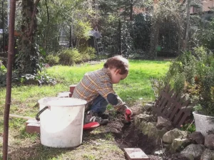 Ogród dla dzieci. Na zdjęciu dziecko bawiące się w ogrodnika.