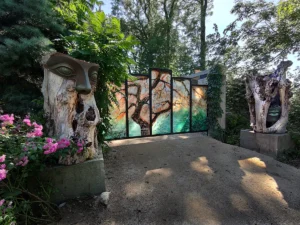 Brama do ogrodu z oszklonymi obrazami, przed nią rzeźby.